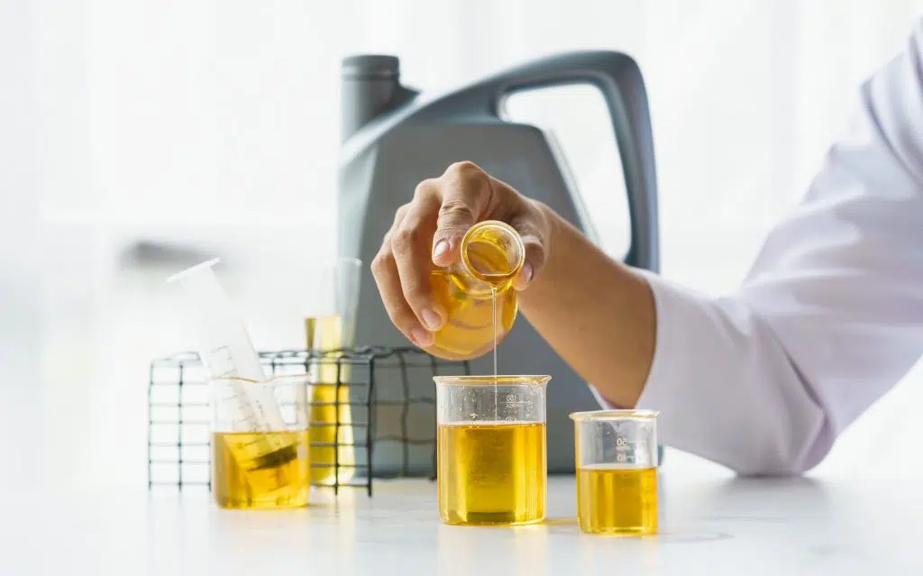Laboratory technician performing an engine oil test and pouring oil during automotive fluid analysis